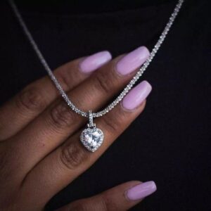 Collier Little Heart argenté, pierre centrale en forme de cœur et contour pavé, présenté sur une main