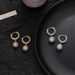 Boucles Ball ICE dorées et argentées avec boules pavées pendantes sur fond noir