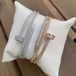 Bracelets Classy Baby argenté et doré au motif de clou pavé posés sur un coussin blanc